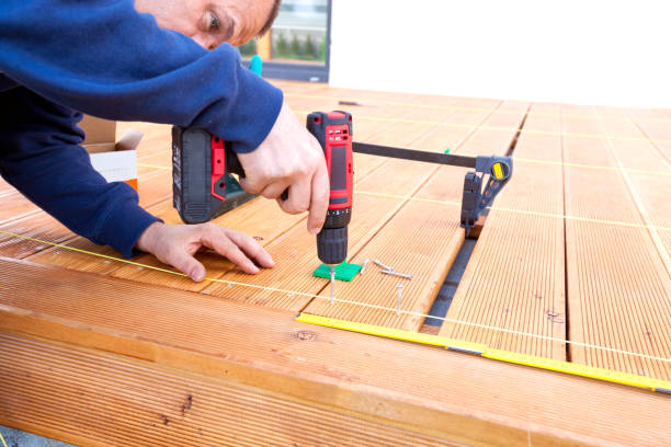 istock Construction worker screwing down wood deck with battery power screw gun or drill. 961371796