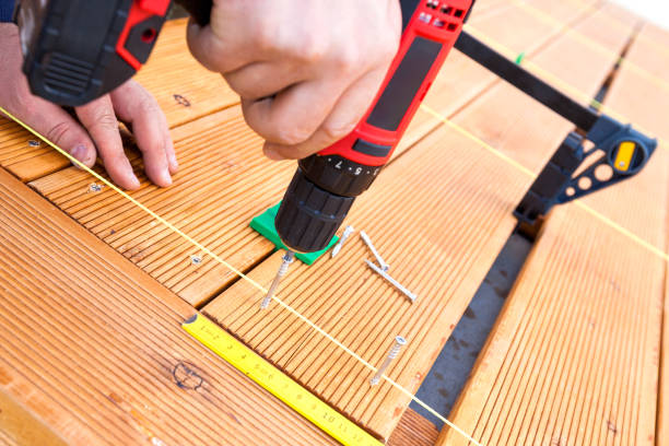 istock Construction worker screwing down wood deck with battery power screw gun or drill. 961371838