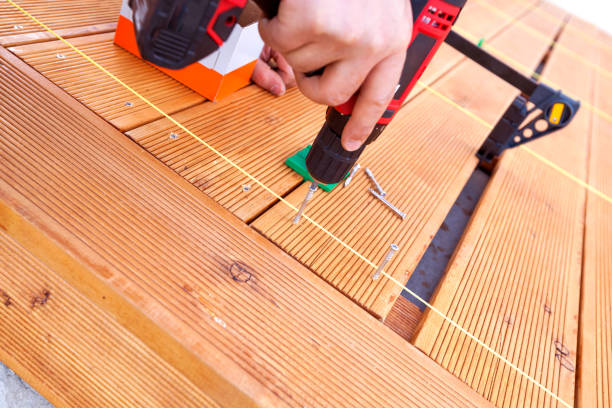 istock Construction worker screwing down wood deck with battery power screw gun or drill. 961371840