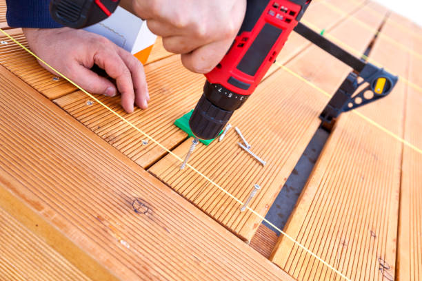 istock Construction worker screwing down wood deck with battery power screw gun or drill. 961371894