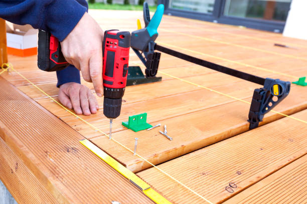 istock Construction worker screwing down wood deck with battery power screw gun or drill. 961371898