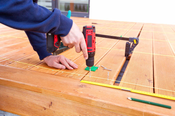 istock Construction worker screwing down wood deck with battery power screw gun or drill. 961371902