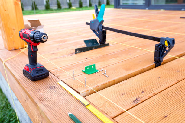 istock Construction worker screwing down wood deck with battery power screw gun or drill. 961371924