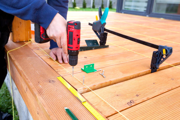 istock Construction worker screwing down wood deck with battery power screw gun or drill. 961372846
