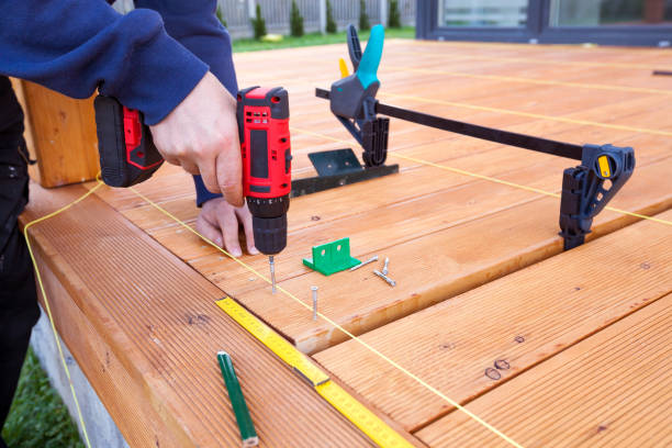 istock Construction worker screwing down wood deck with battery power screw gun or drill. 961373650