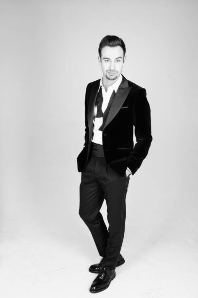 istock Young handsome man in a suit, standing and looking at the camera, bow tie undone 961375590