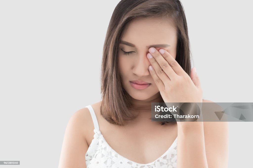 Woman has a pain in the eye Asian woman suffering from strong eye pain against gray background. Female has a pain in the eye. Healthcare concept. Having migraine Eye Stock Photo