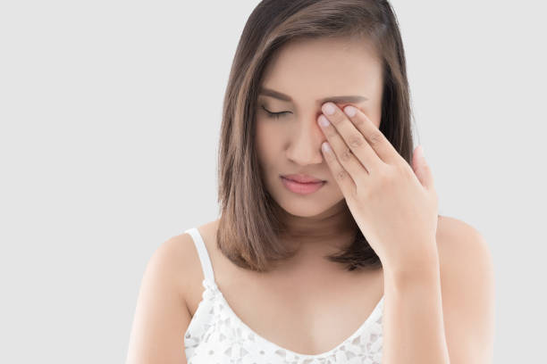 Woman has a pain in the eye Asian woman suffering from strong eye pain against gray background. Female has a pain in the eye. Healthcare concept. Having migraine lymph node photos stock pictures, royalty-free photos & images