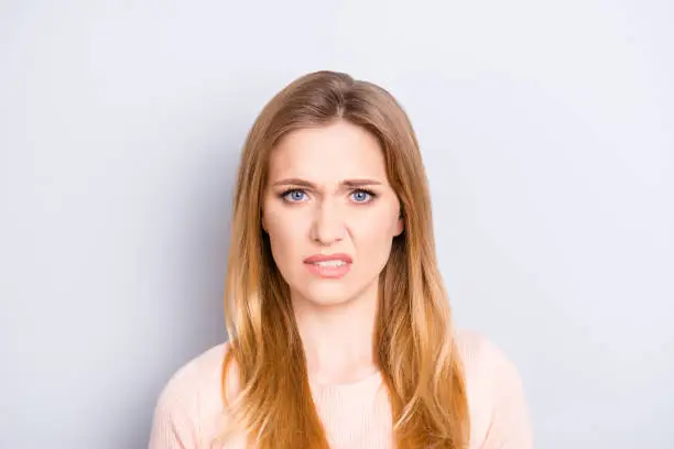 Photo of Close up portrait of funny confused puzzled unhappy upset sad uncertain unsure beautiful pretty charming grimacing woman with long blonde hairdo isolated on gray background opy-space