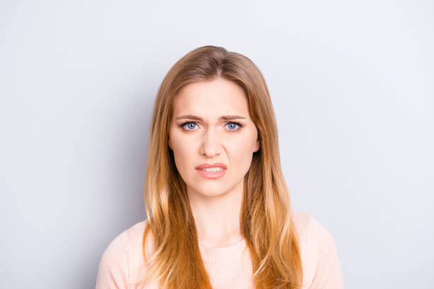 close up portrait of funny confused puzzled unhappy upset sad uncertain unsure beautiful pretty charming grimacing woman with long blonde hairdo isolated on gray background opy-space - frowning imagens e fotografias de stock