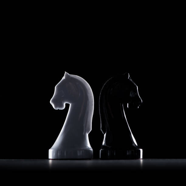 silhouettes of white and black chess knights isolated on black, business concept silhouettes of white and black chess knights isolated on black, business concept black knight stock pictures, royalty-free photos & images
