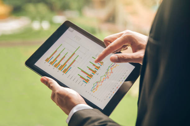 istock Close up businessman hand using tablet and pointing on summary report at office.Male businessman reviews a summary report on tablet. 961395806