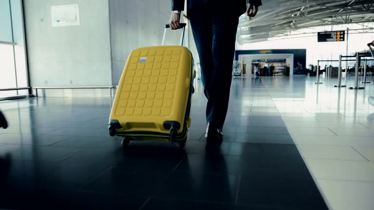 Close-up of businessman walking among travelers' crowd at airport