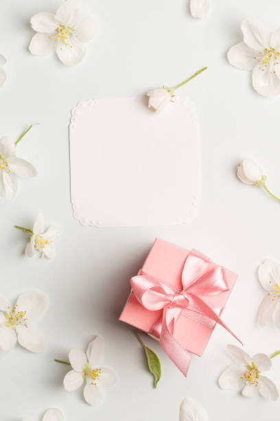 istock pink gift and white card surrounded by Apple flowers. pretty background top view, copy space. love message, congratulations on mother's day, spring, Valentine's day, women's day 961400904