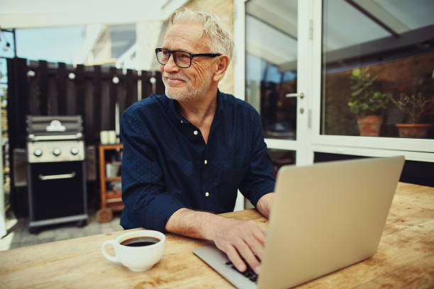 istock Smiling senior man drinking coffee and using a laptop 961405762