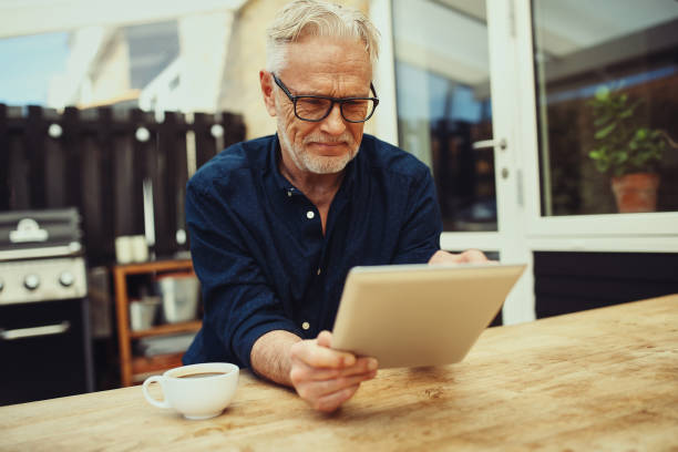 istock Smiling senior man holding a tablet and drinking coffee outside 961406000
