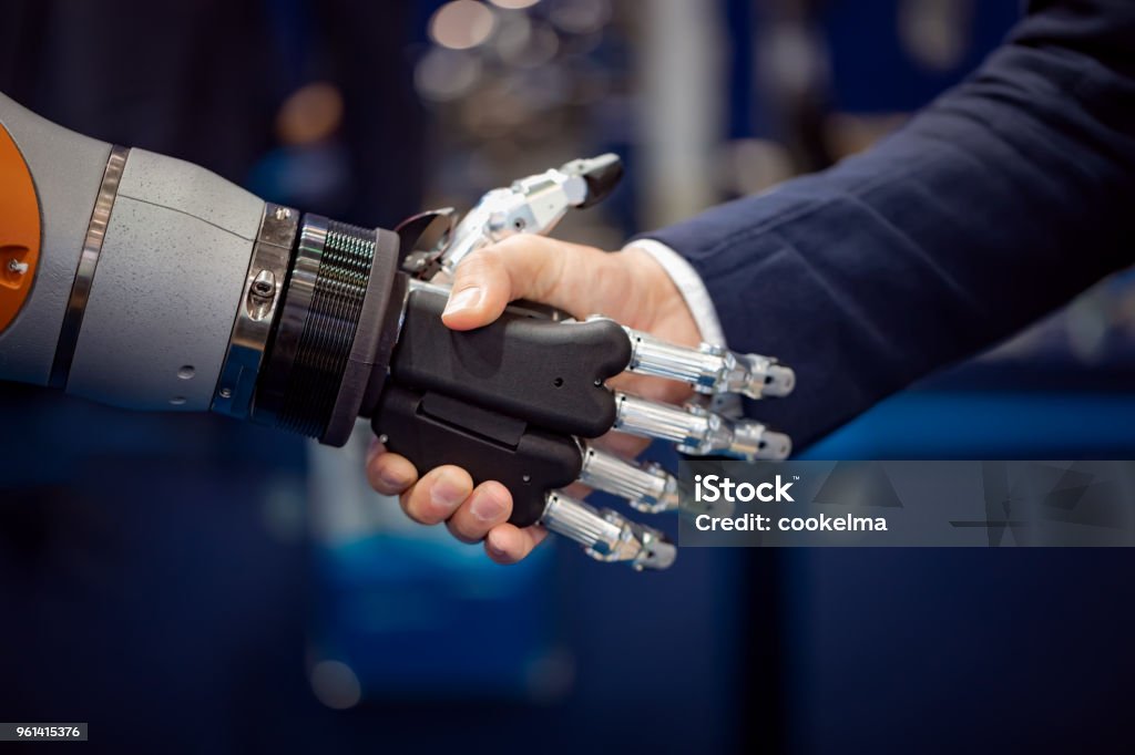 Mano de un empresario sacudariendo las manos con un robot de Android. - Foto de stock de Robot libre de derechos