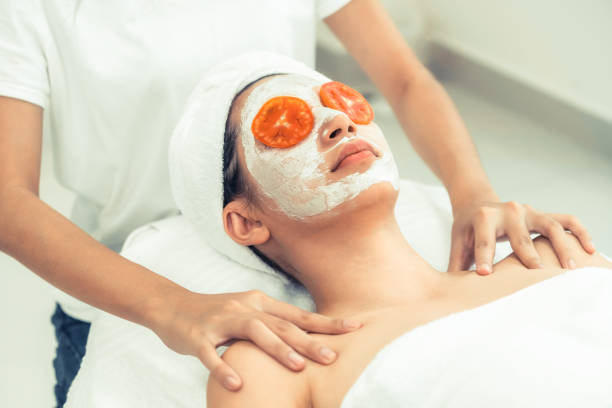 Woman get facial mask with tomato cream extract. Beautiful woman having a facial mask treatment with tomato cream extract showing benefit of nature treatment. Anti-aging cosmetology, facial skin care and luxury lifestyle concept. women facial mask mud cucumber stock pictures, royalty-free photos & images