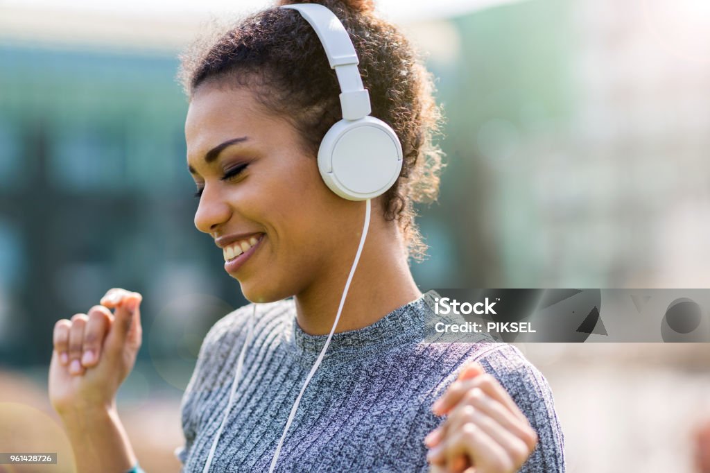 Young woman wearing headphones Happy young woman listening music in headphones in the city Headphones Stock Photo