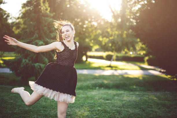 Cheerful young ballerina dancing in the park on a sunny summer day.