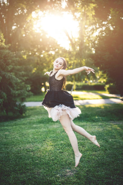 Cheerful young ballerina dancing in the park on a sunny summer day.