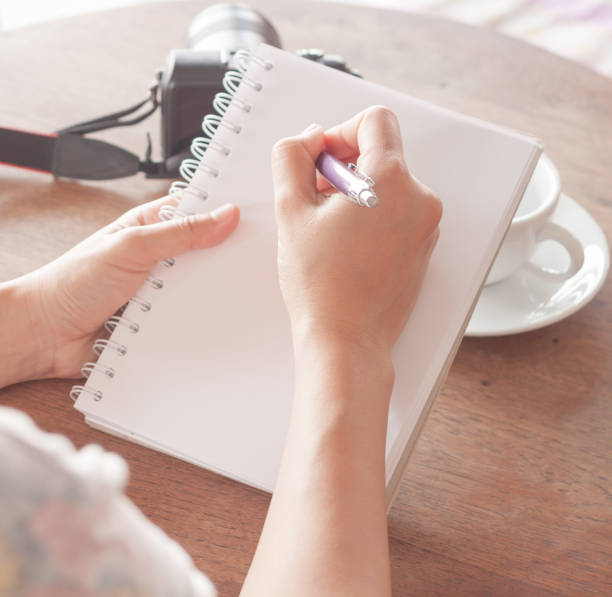 istock Cropped Hands Of Woman Writing On Note Pad At Table 961454322