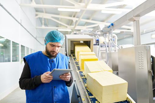 Food factory worker counting butter cubes