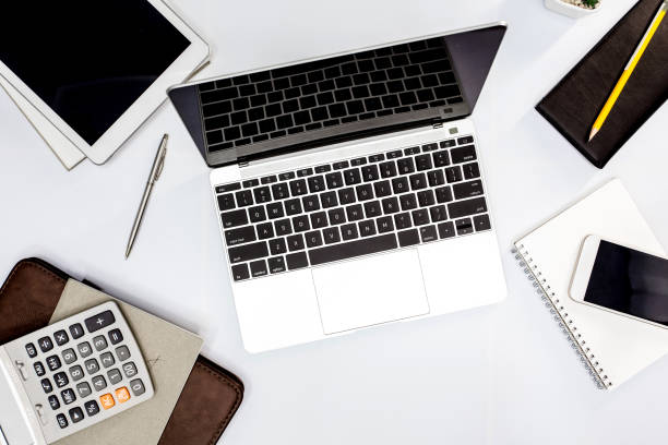 istock White office desk. table with blank notebook, tablet, calculator, computer and other office supplies. Top view with copy space. 961458884