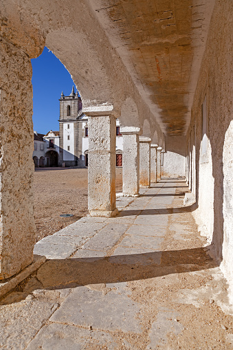 The arcades of the pilgrim lodgings in the Baroque Sanctuary of Nossa Senhora do Cabo, aka Nossa Senhora da Pedra Mua in Espichel Cape and the church at the back. Sesimbra, Portugal