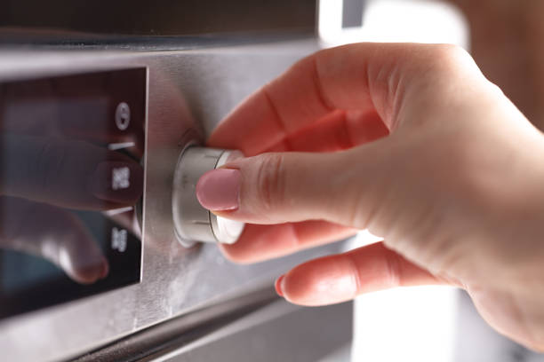 istock Woman Using Microwave Oven For Baking Fresh Cookies In Kitchen 961465626