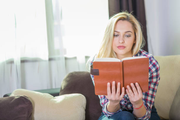 istock Girl on the couch reading a book 961467242