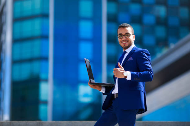 istock Young smiling successful businessman in suit standing on office 961470370