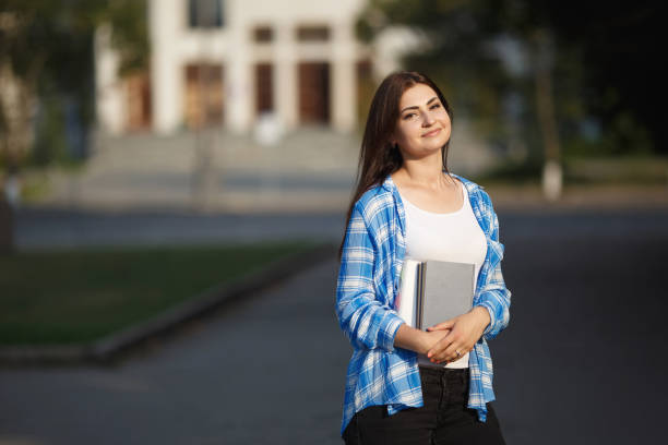 istock Smiling student girl with books and backpack standing on univers 961471016
