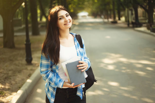 istock Young cute smiling student woman with backpack and books standin 961476604