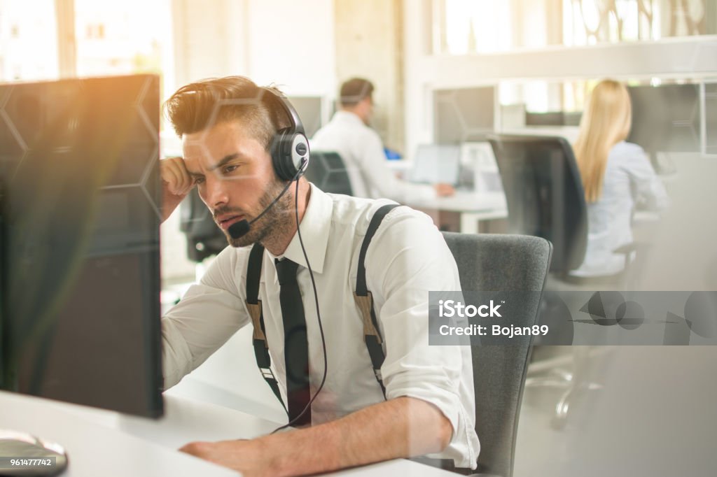 Worried or frustrated business man with headset working on computer in office Call Center Stock Photo
