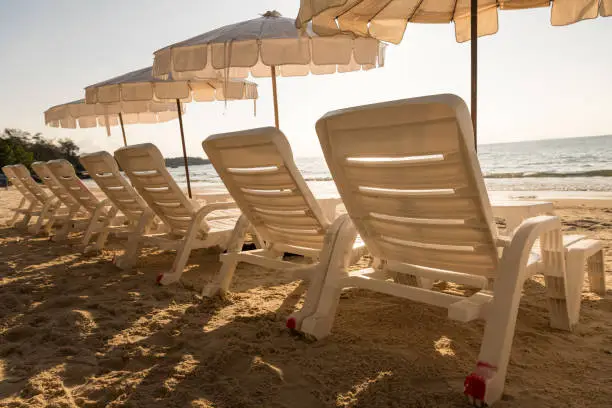 Empty beachchairs under white umbrellas on summer beach.