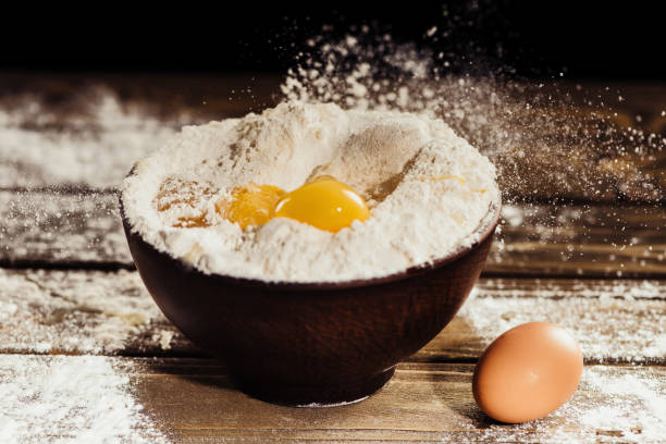 istock yolks falling into bowl with flour on wooden table with one egg near 961488406