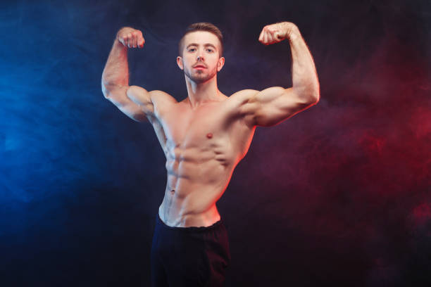 istock Strong young man bodybuilder demonstrating huge muscles on smoke 961490124