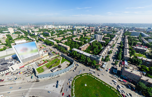 Aerial city view with crossroads and roads, houses, buildings, parks and parking lots, bridges. Copter shot. Panoramic image.