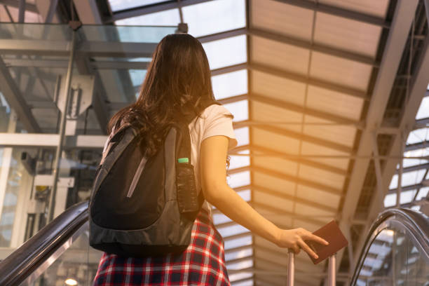 istock Young woman pulling suitcase in modern airport terminal. Travelling guy with his luggage while waiting for transport. Rear view. holiday vacation concept. Copy space. 961501608