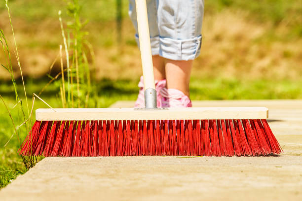 istock Woman using broom to clean up backyard patio 961504626