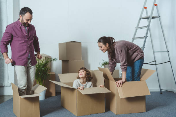istock happy parents looking at son sitting in cardboard box during relocation 961515566