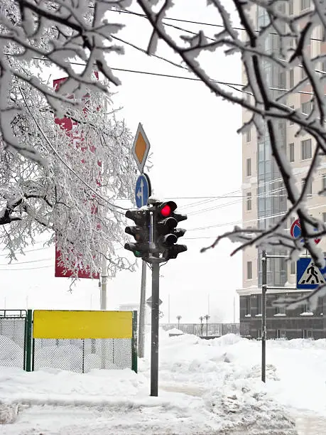 Winter crossroads with traffic lights, snow drifts, road signs.