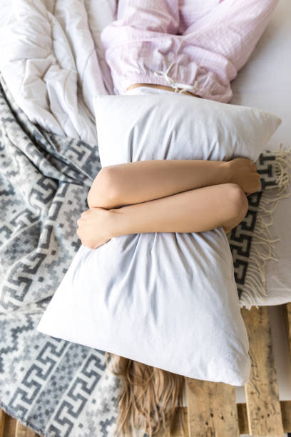 istock obscured view of woman hugging pillow while lying in bed 961519778