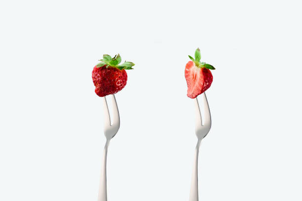 istock cut and whole strawberries on forks isolated on white 961521068