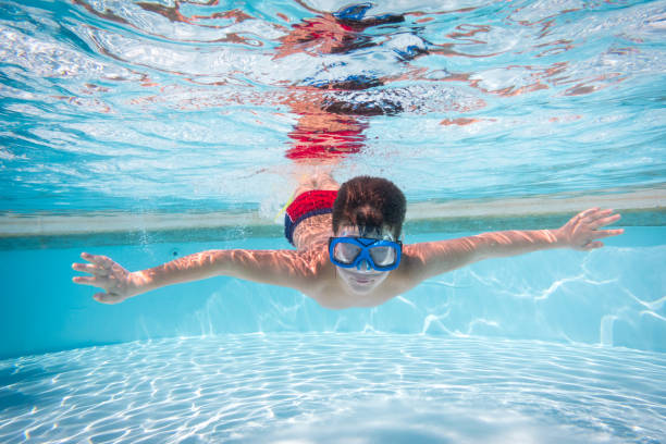 istock Boy in mask dive in swimming pool 961523452