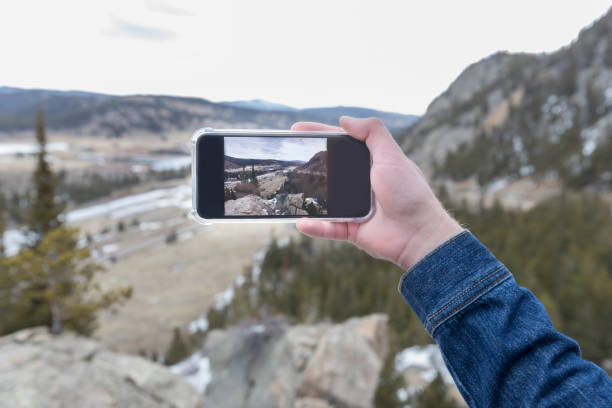 Personal perspective of a man taking a photo with smart phone while on a mountain hike.