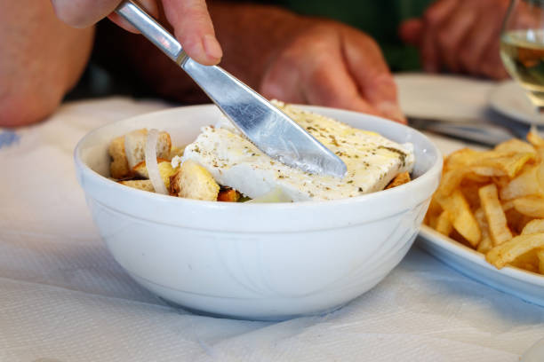 Woman cutting feta Greek cheese.