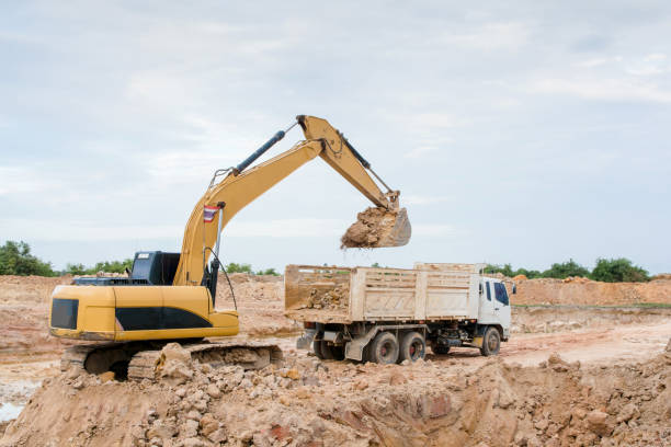 istock Yellow excavator machine loading soil into a dump truck at construction site 961525782