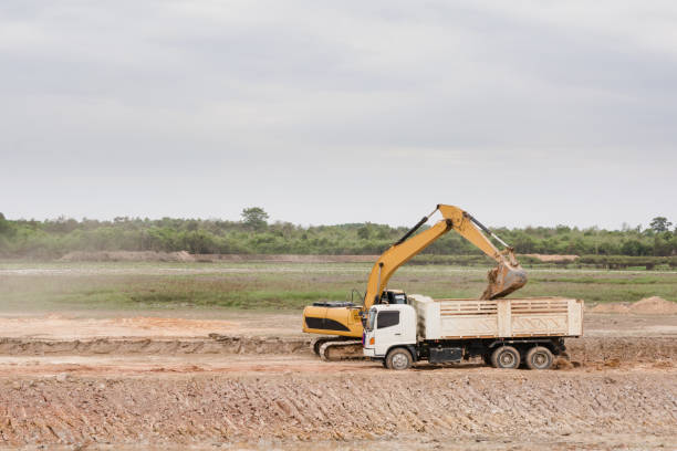 istock Yellow excavator machine loading soil into a dump truck at construction site 961529140